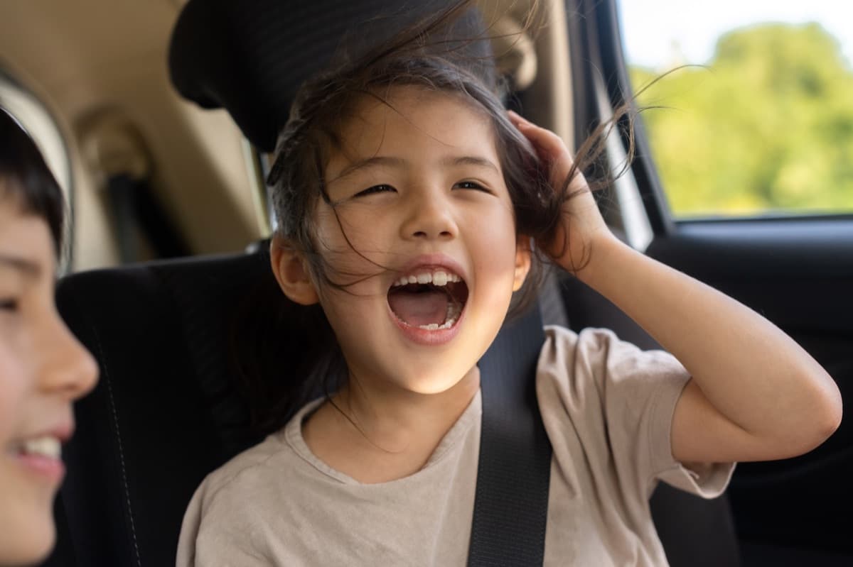 A child laughing in the back seat of a car